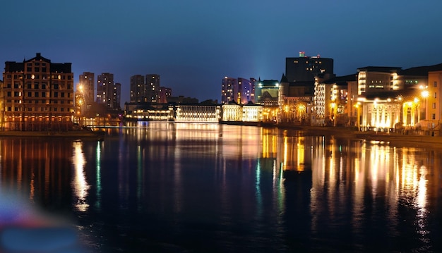 Photo the night city stands on the river and the lights of the windows can be seen in the reflecti