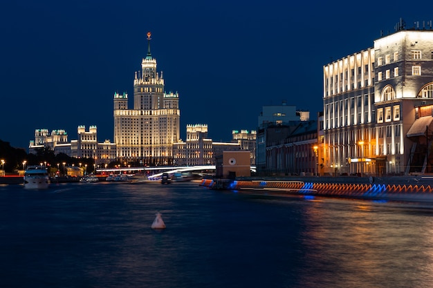 Night cityscape featuring brightly lighted empire style skyscraper on a riverbank