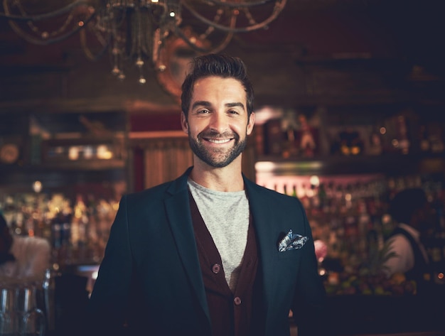 night confidence and portrait of man in pub with smile for weekend culture social networking and fun gentleman face and manager at trendy bar in nightclub with pride cool fashion and happy hour