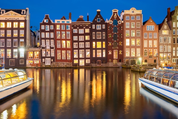 Night dancing houses at Amsterdam canal Damrak, Holland, Netherlands.