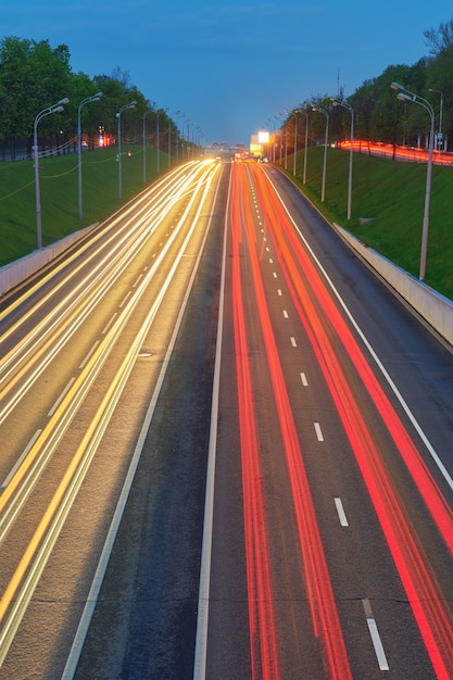 車のライトが付いている夜の高速道路道路。スピードトラフィックのある道路の黄色と赤のライトトレイル。長時間露光抽象的な都市の背景