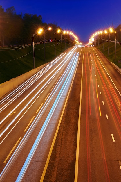 車のライトが付いている夜の高速道路道路。スピードトラフィックのある道路の黄色と赤のライトトレイル。長時間露光抽象的な都市の背景