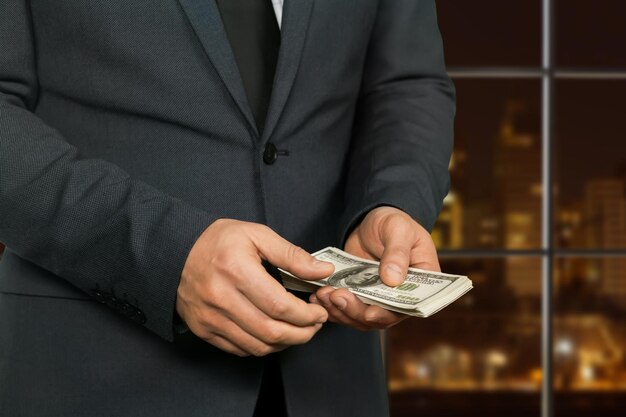 Night hotel manager counting money. Megalopolis businessman counts dollars. Hands of criminal. Far from the law&amp;#39;s eyes.