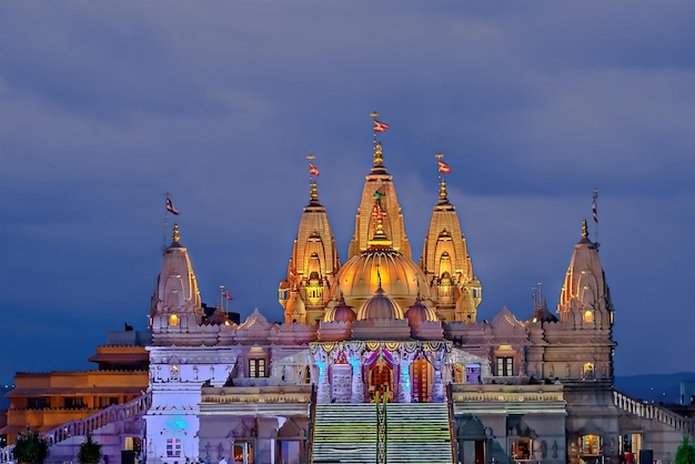 night illuminated shree swaminarayan temple with dark blue clouds background pune