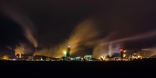 Foto paesaggio industriale notturno inquinamento ambientale rifiuti della centrale termica grandi tubi dell'impianto industriale dell'industria chimica