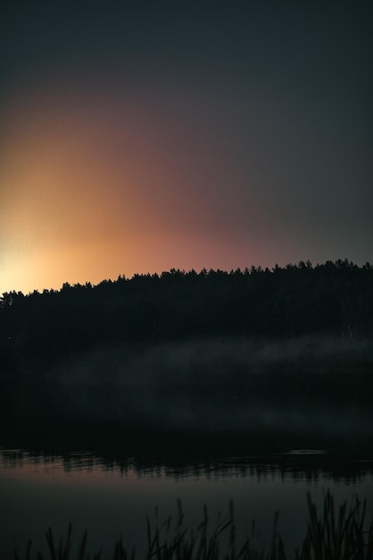 Night at the lake Smoke on the water during the late evening Forest reflection in the water with mist