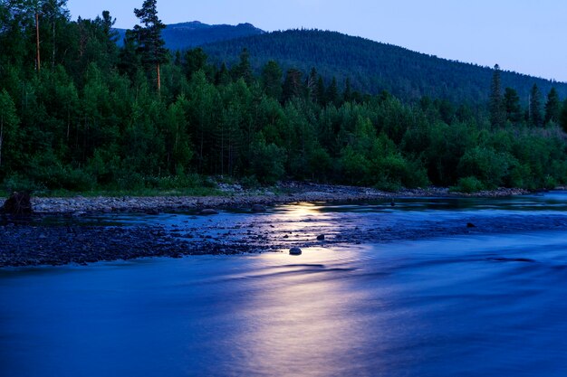Photo night landscape - a reflection of the moon in the river among the forest in the ural mountains