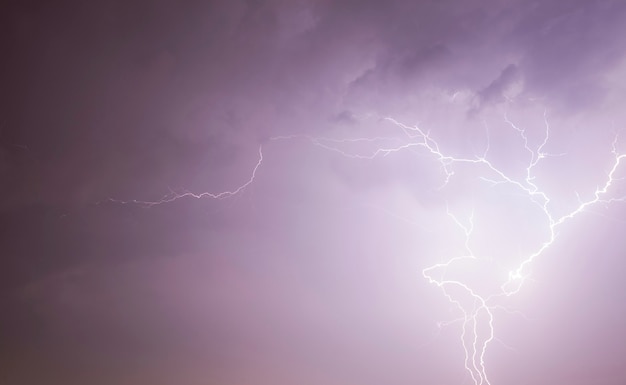 Night landscape with black sky illuminated by lightning discharge during thunderstorms, real windy and rainy weather