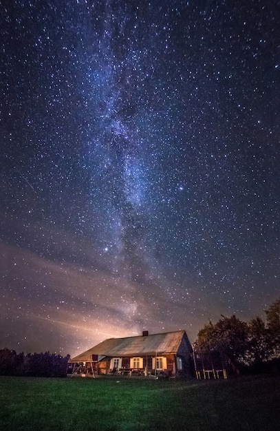 사진 은하수 별이있는 밤 풍경은 도시 외부의 시골 집에 있습니다.