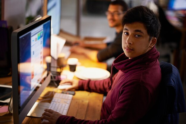 Night office and portrait of man with computer for online work as programmer or software developer for company Male person serious and technology for cloud engineer for websites and app designs