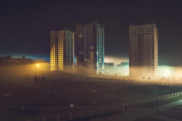 早朝の霧の中の高層ビルのある住宅街の夜景