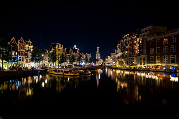 写真 運河の反射と伝統的なオランダの家とボートのあるアムステルダムの夜の写真