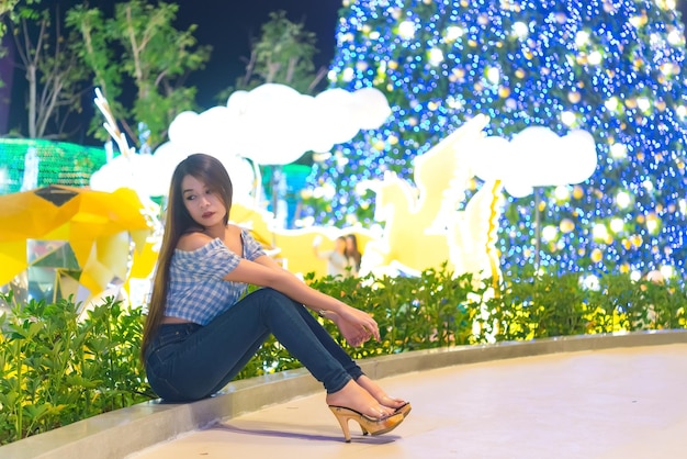 Night portrait of beautiful asian womanThailand girl pose for take a photo on bokeh light at night