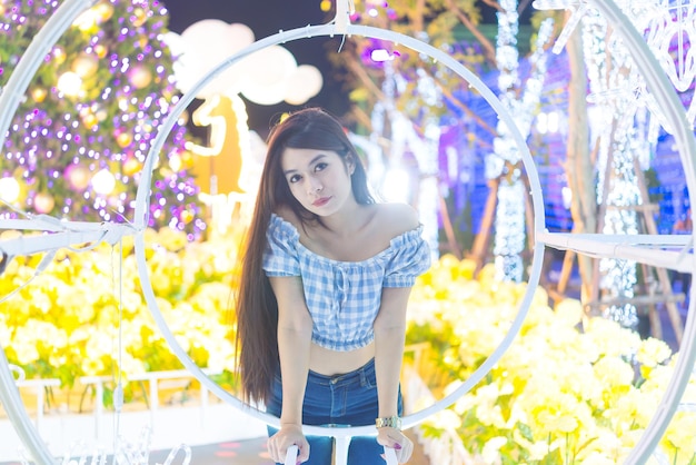 Night portrait of beautiful asian womanThailand girl pose for take a photo on bokeh light at night