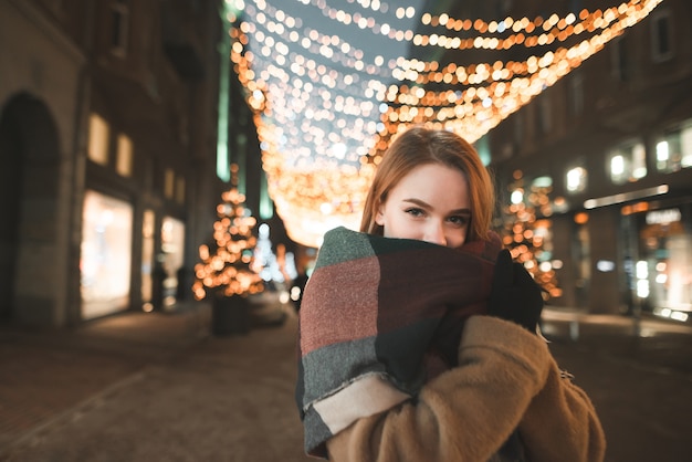 Night portrait of a cute warm clothing girl on the background of the city and the lights of the scenery