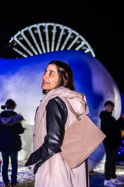 Foto ritratto notturno di una bella donna sorridente che si gode un viaggio attraverso un parco di natale a dicembre