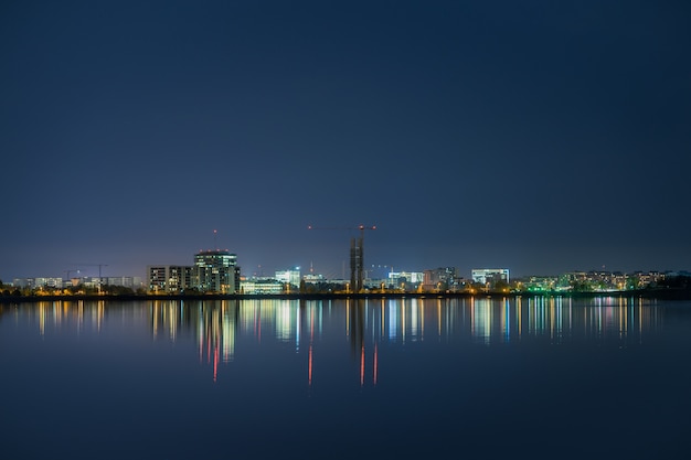 Night scene with city view and reflections in lake.