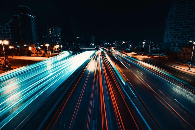 A night shot of a highway with lights on and a city in the background