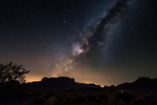 Night sky full of stars and surrounded by the silhouette of mountains over desert