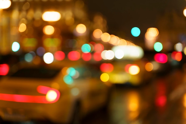 Ночные уличные фонари размывают автомобили, транспорт и такси и движение на вечерней городской дороге