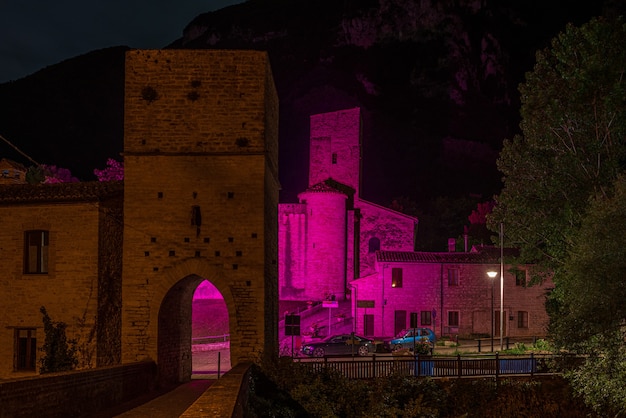 Night view of medieval village on river, san vittore frasassi,\
marche, italy. romantic sky and clouds above mountains landscape,\
tourism destination.