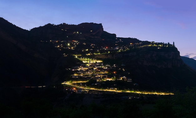 崖の上に輝く提灯がある山の村の夜景