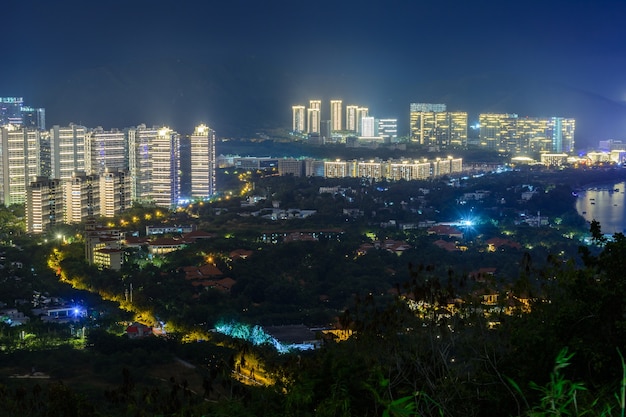 Night view of Sanya city with bright multi-colored illumination buildings, structures, roads, sidewalks, poles, bridges. Sanya, Hainan, China