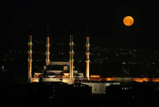 Photo a night with a full moon in the sky above kocatepe mosque