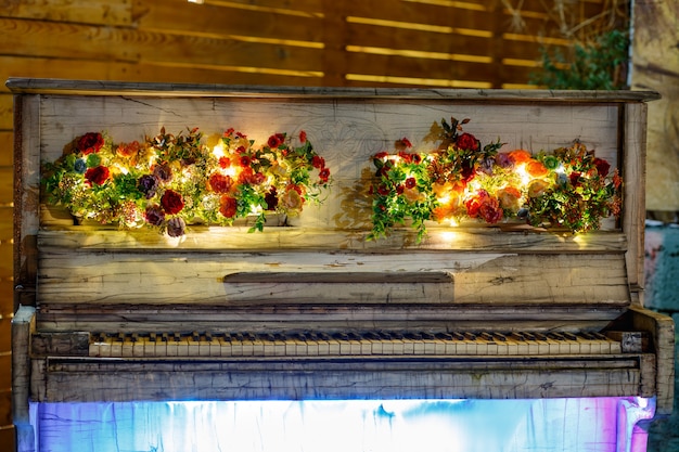 Nightshot of decorative retro white piano with led lights decorated with flower ornaments