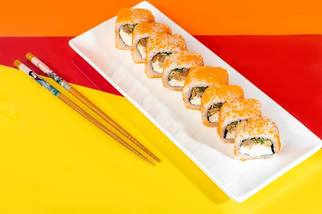 Nigiri sushi sets Uramaki California Philadelphia on a white plate Near ginger and wasabi Soy sauce in a white bowl On a colored background