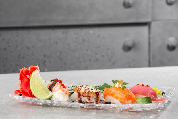 Nigiri sushi with salmon, eel, tuna and prawn, served on transparent plate.