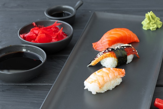 Nigirisushi met zalm, paling en garnalen die op zwarte ceramische plaat worden gediend