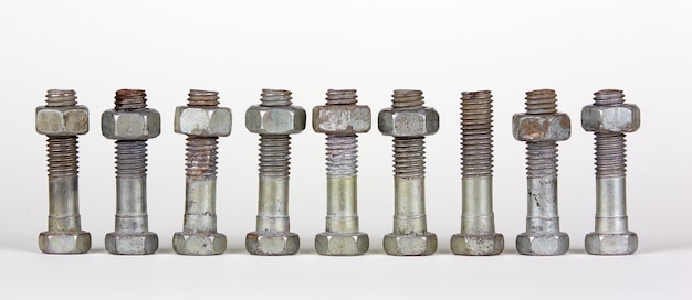 Nine bolts with nuts in a row. One object is an exception.