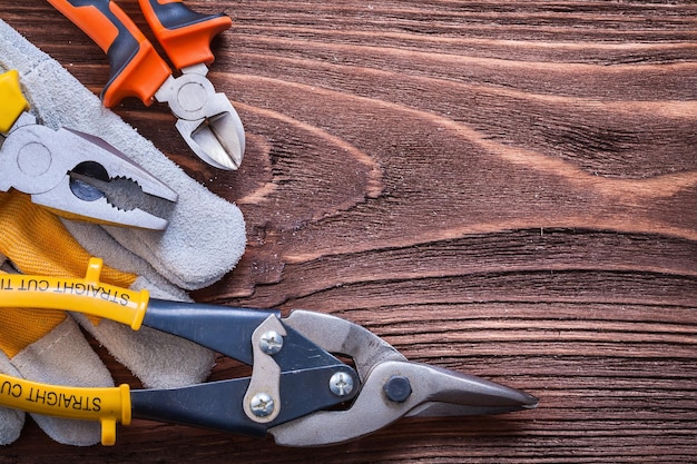 Nippers pliers wirecutter and protective glove on wood board construction concept