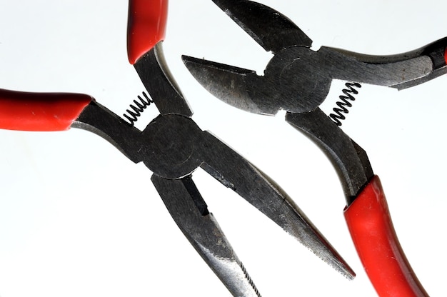 Nippers and pliers with red handles on a light background close-up.