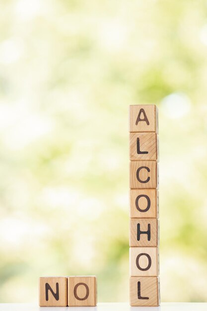 No alcohol is written on wooden cubes on a green summer background Closeup of wooden elements