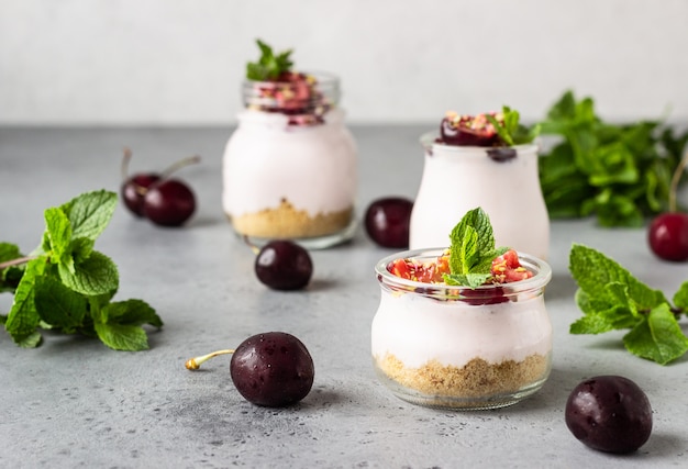 No baked cheesecake with cherry in glass jars, fresh cherries and mint