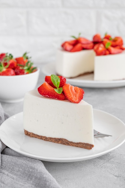 Nessuna cheesecake al forno con fragole fresche e menta in cima su un piatto bianco copia spazio