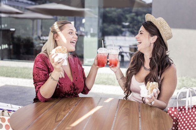 Nessuna dieta. belle donne felici che si sorridono l'un l'altra mentre si godono il loro pasto malsano