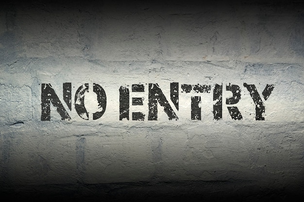 No entry black stencil print on the grunge brick wall with gradient effect