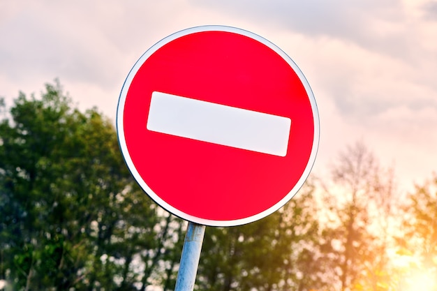 No Entry road sign agains the sky. The road is closed red round sign. White brick in red circle road sign.