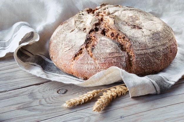 リネンタオルスペルト小麦の耳で木のまな板に手作りのパンをこねないでください