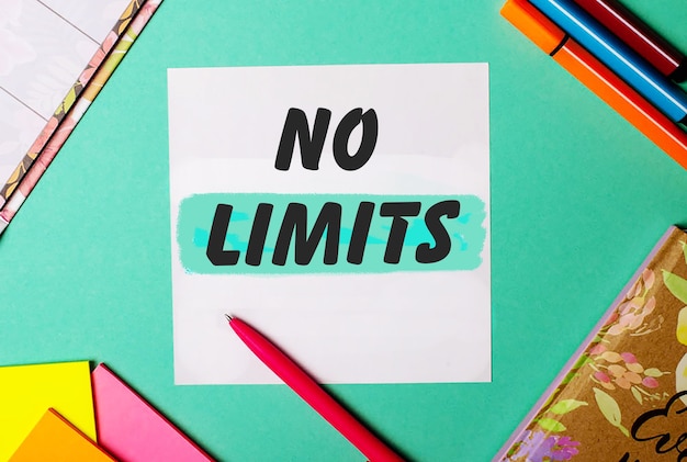 NO LIMITS written on a turquoise surface near bright stickers, notepads and markers