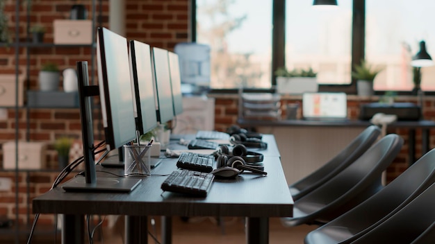 No people at desk with monitors and headphones, workspace prepared for telework communication at call center company. Empty workstation with computers and headsets at customer service.