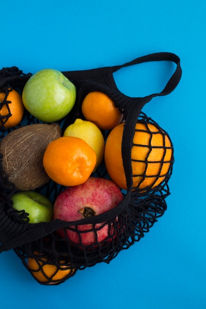 Photo no plastic bag concept. mesh shopping black bag with different fruits on the blue