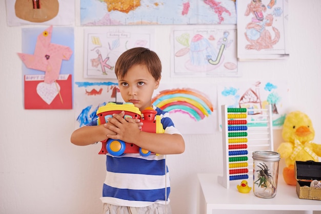 共有しないおもちゃのトラックを胸に抱きしめている少年