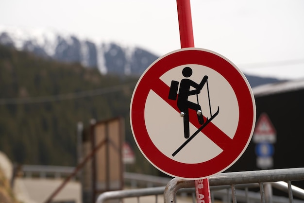 A no ski climbing sign prominently displayed against a backdrop of distant mountains and a metal barrier Amidst nature s beauty lies danger heed the warning signs to ensure a safe experience