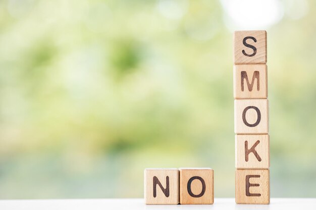 No smoking is written on wooden cubes on a green summer background Closeup of wooden elements