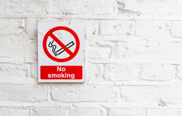 No smoking sign on a white brick wall copy space for individual text