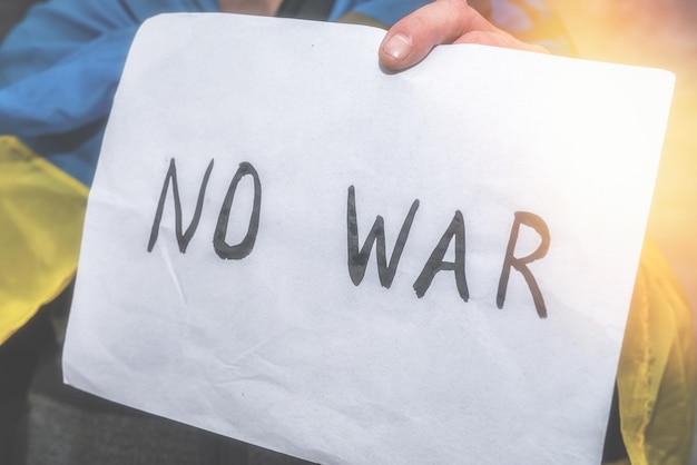 No war written on a poster that a man holds in ukraine russia to the aggressor and the international theorist